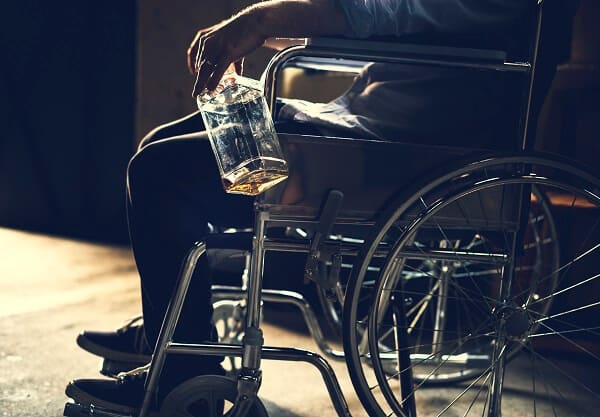 alkoholik siedzący na wózku inwalidzkim